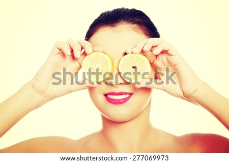 Portrait of nude woman with lemon on eyes.