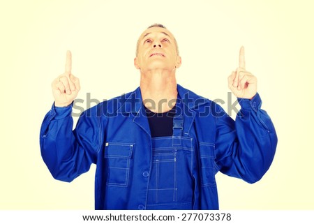 Mature repairman pointing up with both hands.