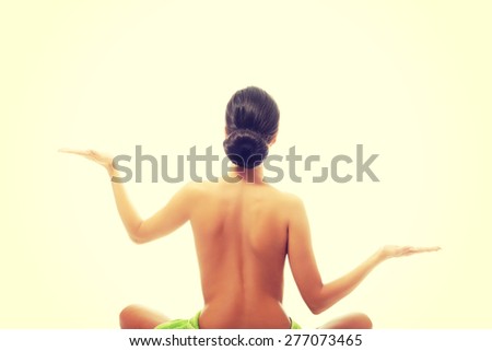 Back view woman sitting excercising yoga.