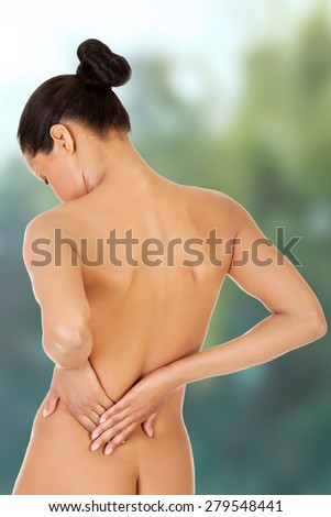 Beautiful woman is touching her lower back.