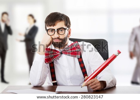 Worried old fashioned man sitting by a desk writing with big pencil.