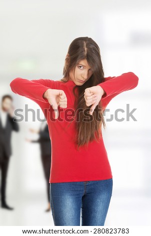 Unhappy young woman with thumbs down.