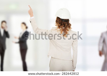 Architect businesswoman in white helmet pointing up.
