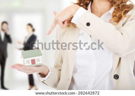 Businesswoman pointing on a model house in hand.