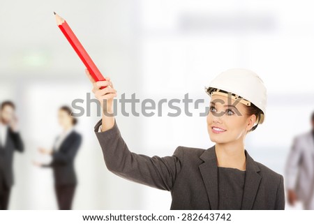 Businesswoman in hard hat pointing up with pencil.
