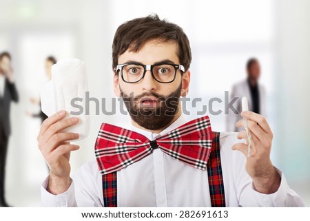 Surprised man wearing suspenders with menstruation pad.