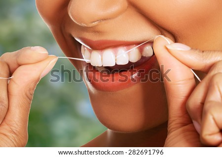Happy young woman flossing teeth.