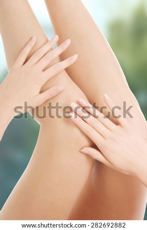 Woman touching her smooth legs after depilation.