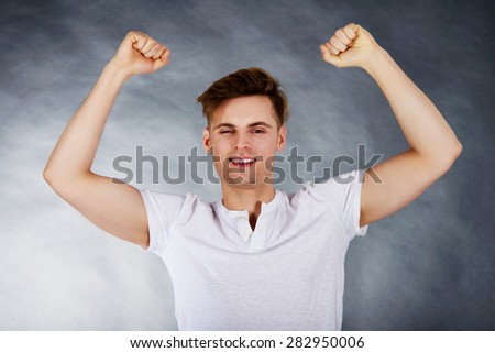 Young happy man with hands up in a winner gesture.