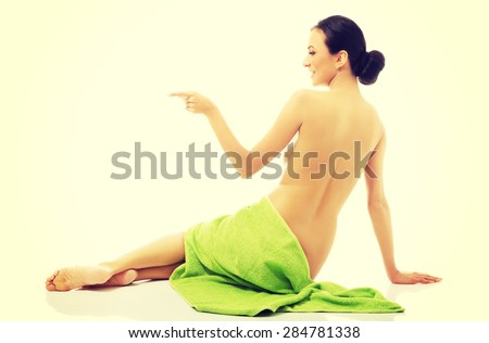 Back view woman wrapped in towel pointing left.