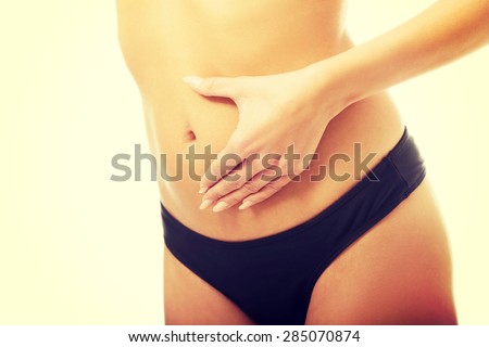 Tanned woman touching her slim belly.