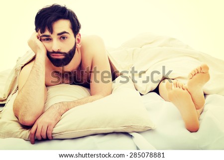 Young handsome depressed man in bed.