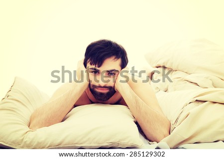Depressed young man lying in bed.