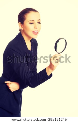 Smiling businesswoman looking through magnifying glass.