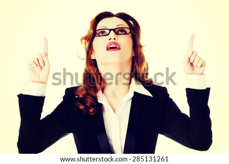 Beautiful businesswoman in eyeglasses pointing up.