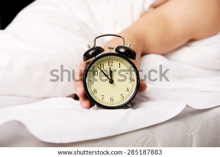Man lying on the bed with alarm clock.