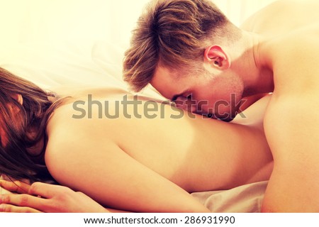 Man kissing woman in her back on bed.