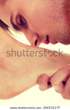 Handsome young man kissing woman's bare feet.