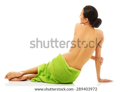 Spa woman sitting wrapped in towel back to camera.
