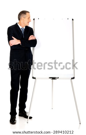 Mature businessman with marker standing near flip chart.