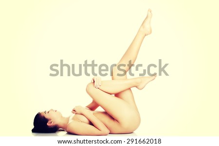 Slim naked woman lying down with legs up