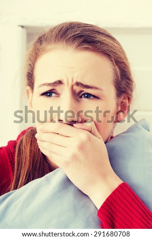 Beautiful caucasian scared woman holding a pillow