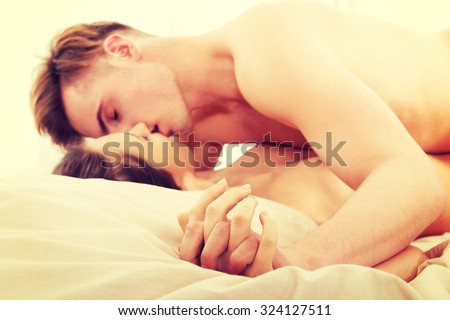 Young caucasian couple kissing on bed.