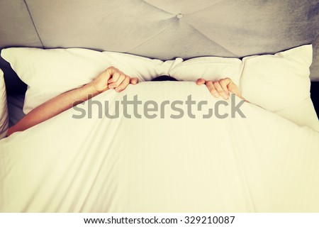 Funny man hiding in bed under the sheets.
