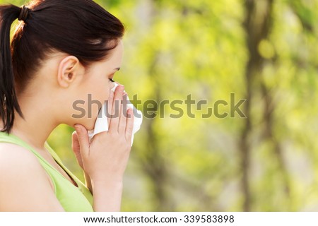 Attractive woman outdoor with tissue having allergy.