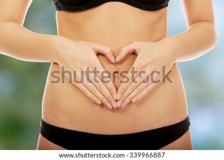 Woman make heart with hands on belly.