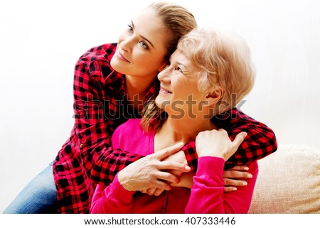 Senior woman with granddaughter or  daughter hugging on couch