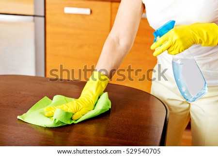 Elderly woman in yellow gloves cleaning table
