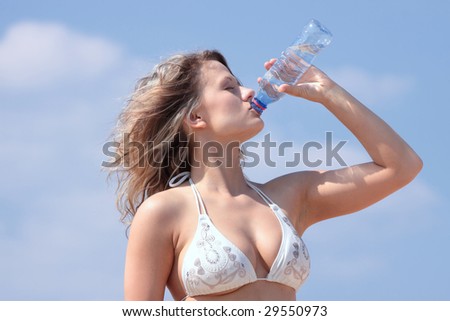Young woman in bikini drinking water after fitness exercise or sunbathing