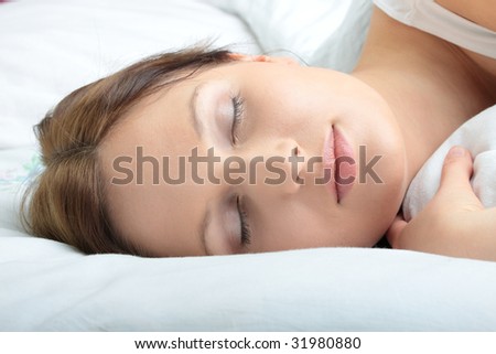 Portrait of the beautiful young woman sleeping in white bed