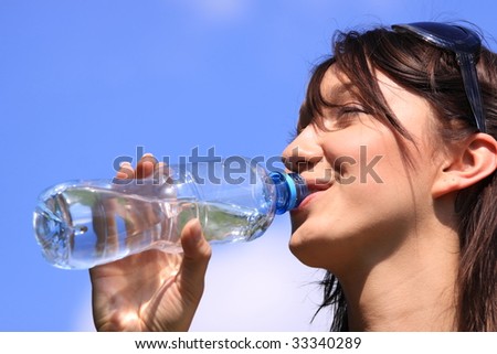 Girl drinking water against blue sky in sunny day