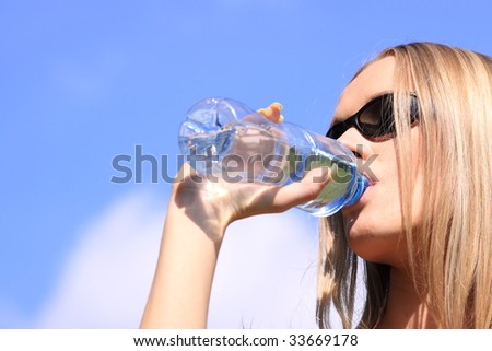 Girl drinking water against blue sky in sunny day