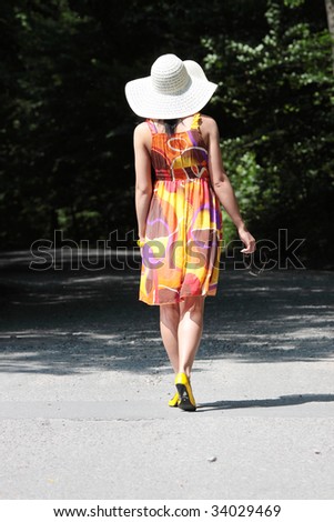 a beautiful girl wearing summer dress and big hat in the country