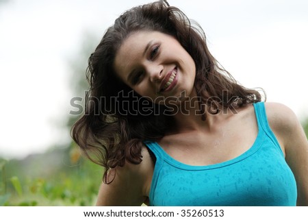 Beautiful young woman relaxing in the grass (rain in summer)