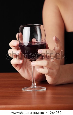 Young woman with glass of red wine, isolated on black background
