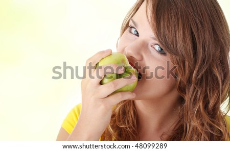Teen girl eating green apple over green background