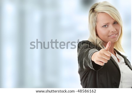 Attractive blonde woman in professional business suit standing and pointing her thumbs up smiling