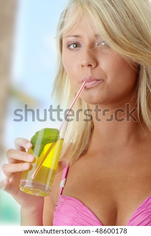Beautiful young woman in pink bikini with cold drink (green tea)