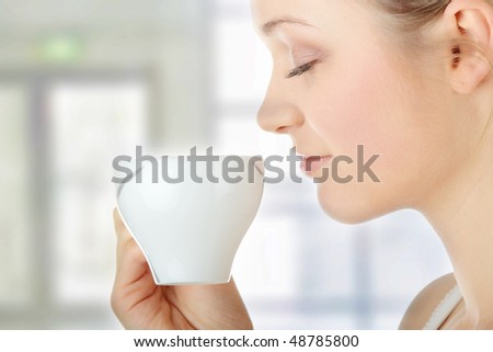 Young attractive blond woman drinking coffee in office - blurred background