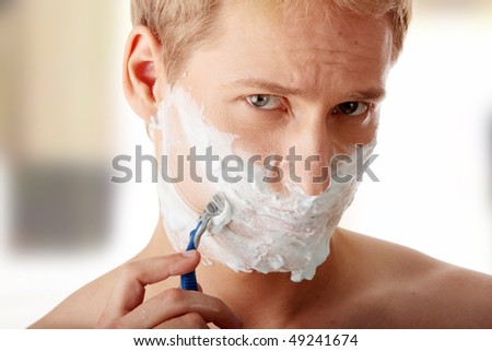 Young caucasian man is shaving his self
