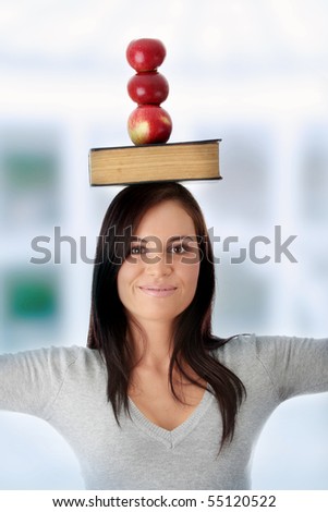 Beautiful student woman have book and apple on her head - learning concept
