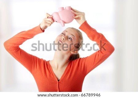 Young blond woman trying to get money from her piggy bank