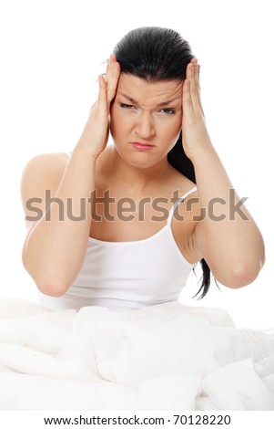 Young caucasian female sitting on bed. She have terrible headache (illness or hangover). Isolated on white