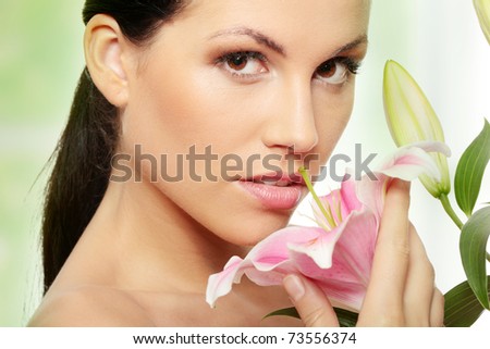 Beautiful young woman face with perfect skin with lily flower.