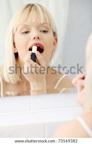Woman making up her lips at bathroom