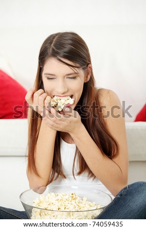 Young woman\'s eating popcorn. In home.